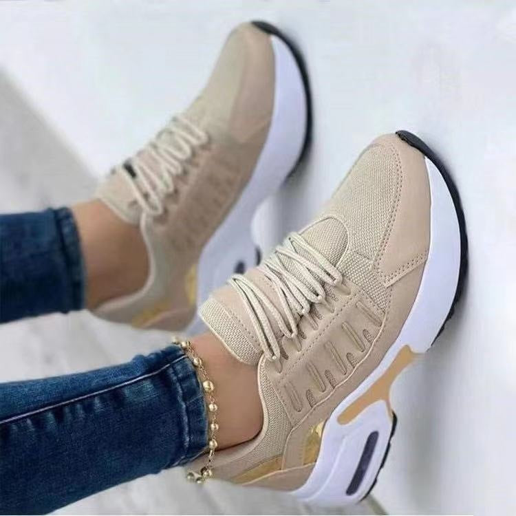 Beige sneakers worn with blue jeans on a white background