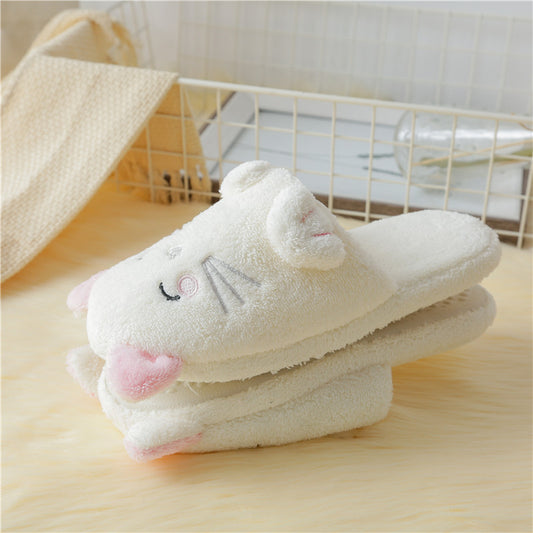 Pair of white cartoon slippers with pink accents on a wooden surface.