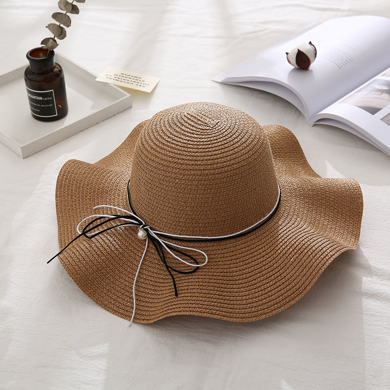 Brown straw hat with a decorative ribbon on a light surface.