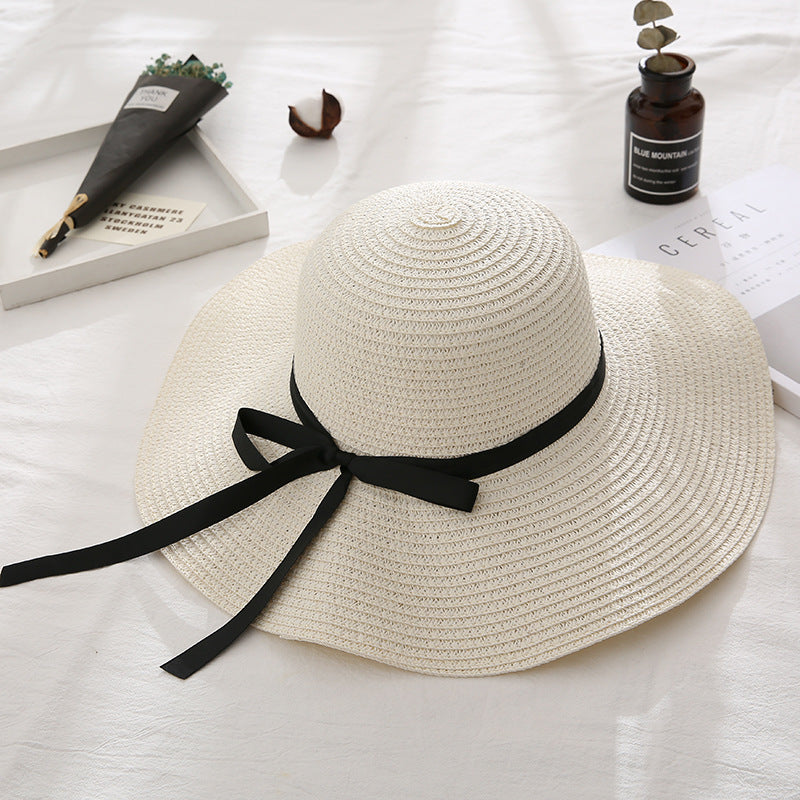 Beige straw hat with a black ribbon on a light surface