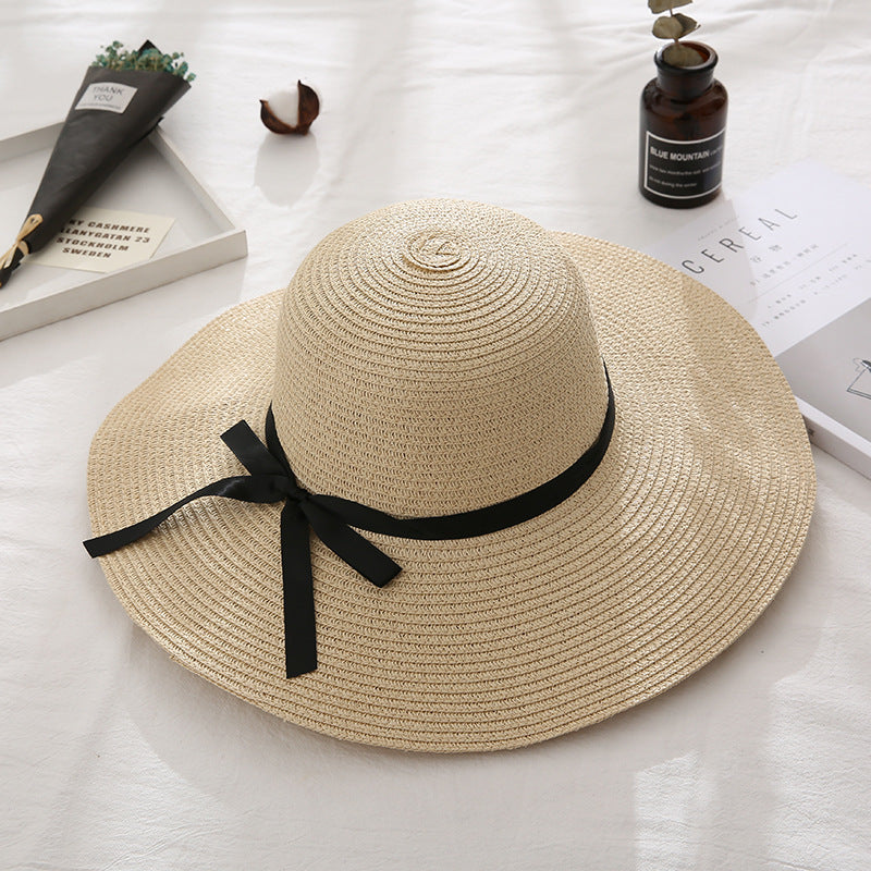 Beige straw hat with a black ribbon on a light surface