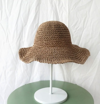 Brown woven hat on a white stand against a white background