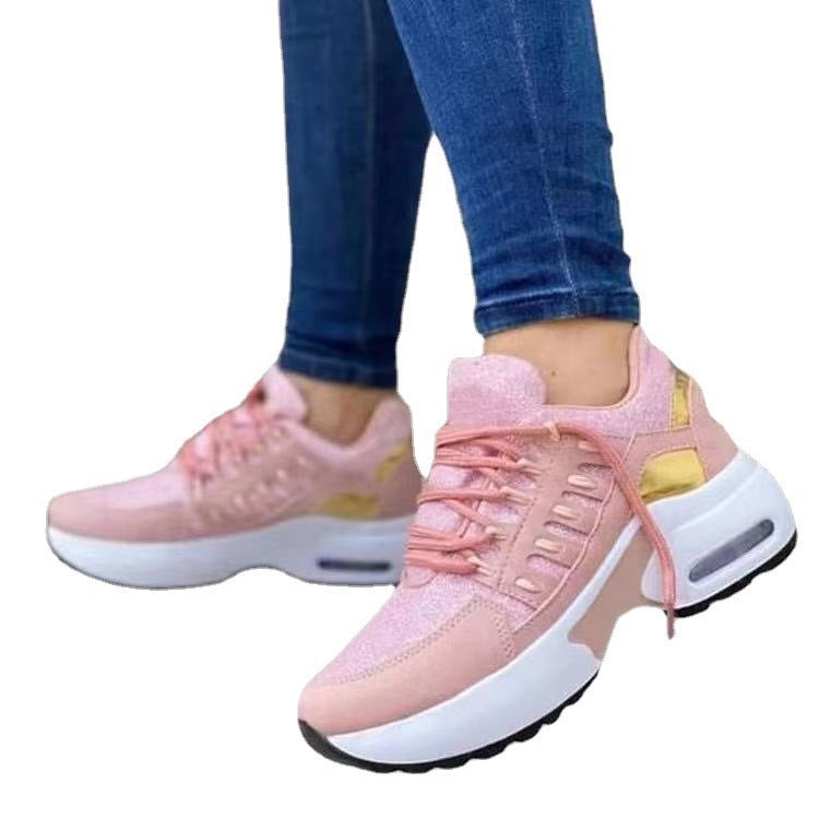 Pink sneakers with white soles worn with blue jeans on a white background