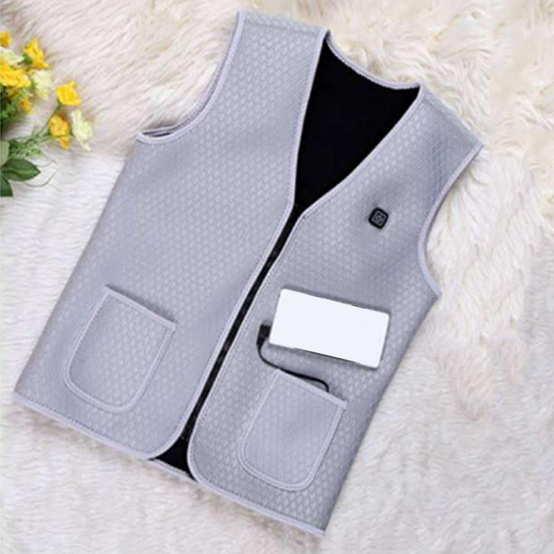 Gray electric heating vest on a white surface with flowers in the corner