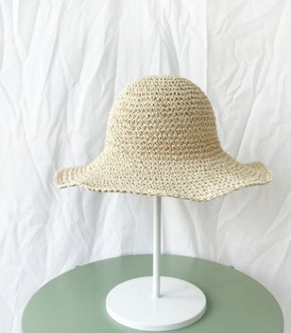 Beige straw hat on a white stand against a white background