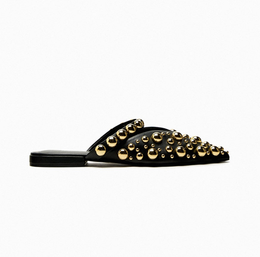 Black sandal with gold studs on a white background