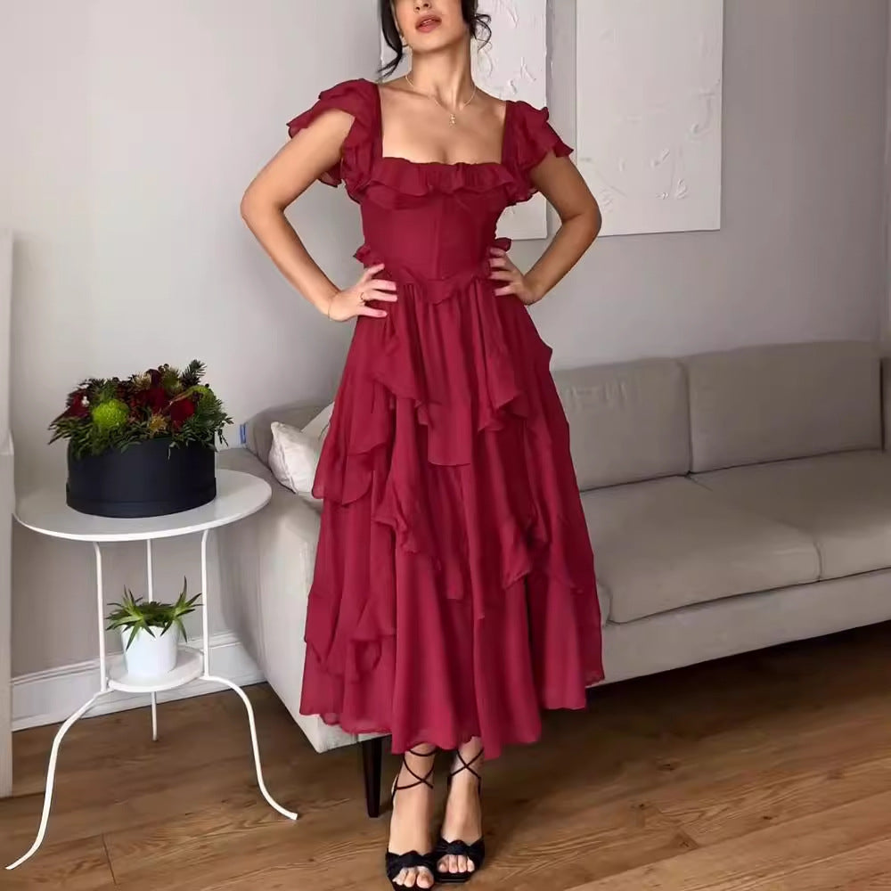 Woman in a red dress standing in a living room with a couch and small table.