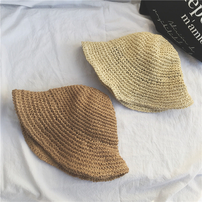 Two woven hats in beige and brown on a white fabric background