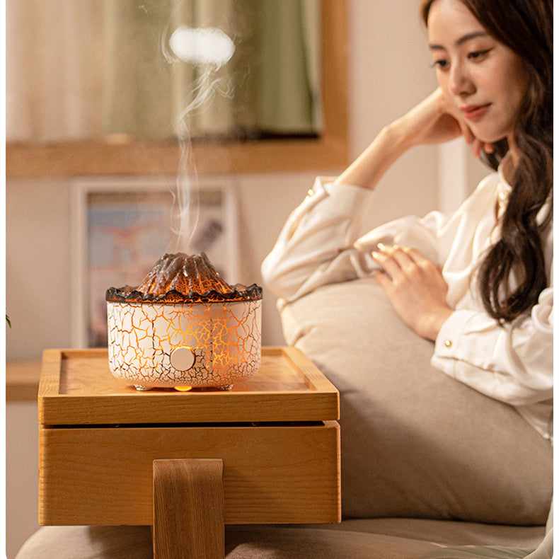 Woman sitting on a couch with a crackled glass diffuser emitting steam.