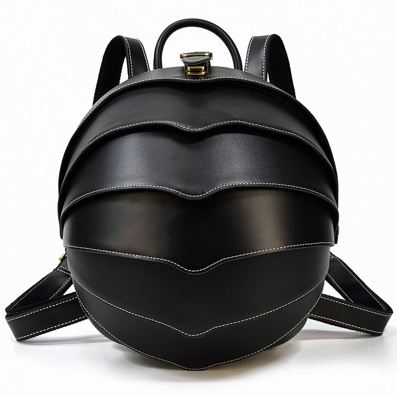 Stylish black leather backpack with beetle-inspired design on a city street – ideal for travel and daily use