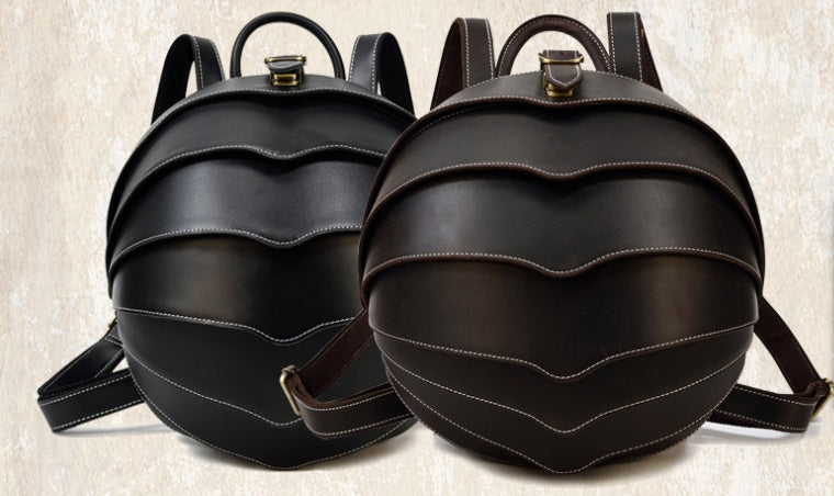 Stylish black and brown leather backpack with beetle-inspired design on a city street – ideal for travel and daily use
