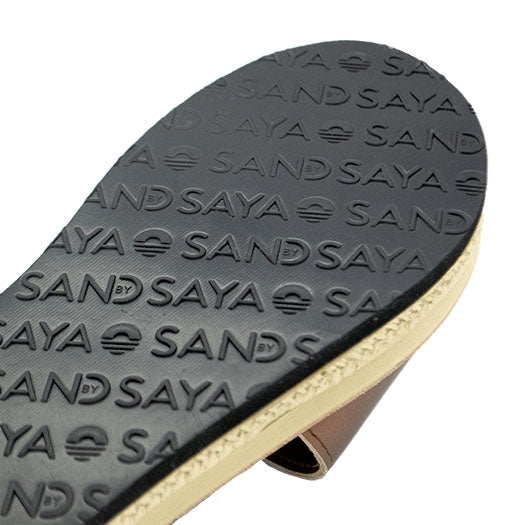 Close-up of a sandal sole with 'SAND SAYA' branding on a white background