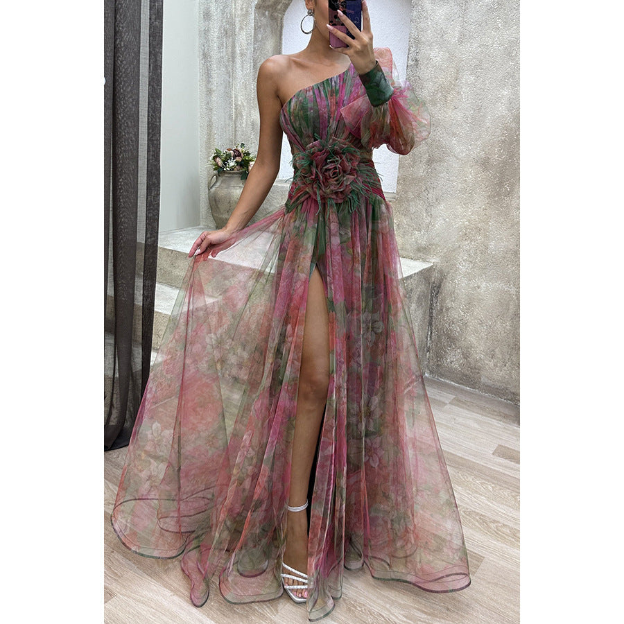 Woman wearing a floral one-shoulder dress with a high slit in a room.
