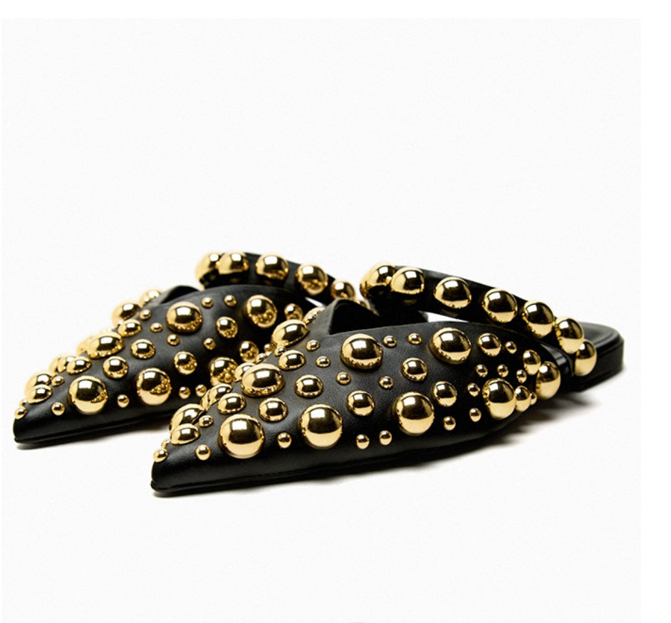 Black slide sandals with gold studs on a white background
