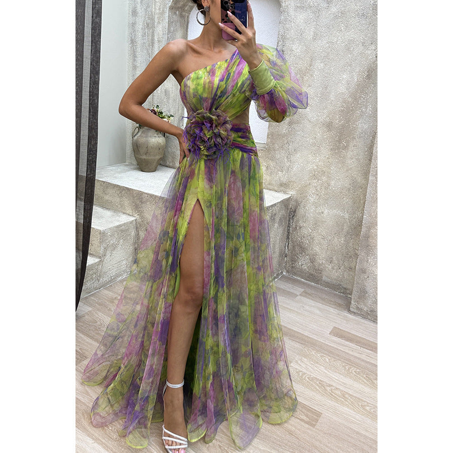 Woman wearing a green and purple floral dress with a slit, standing in front of a mirror.
