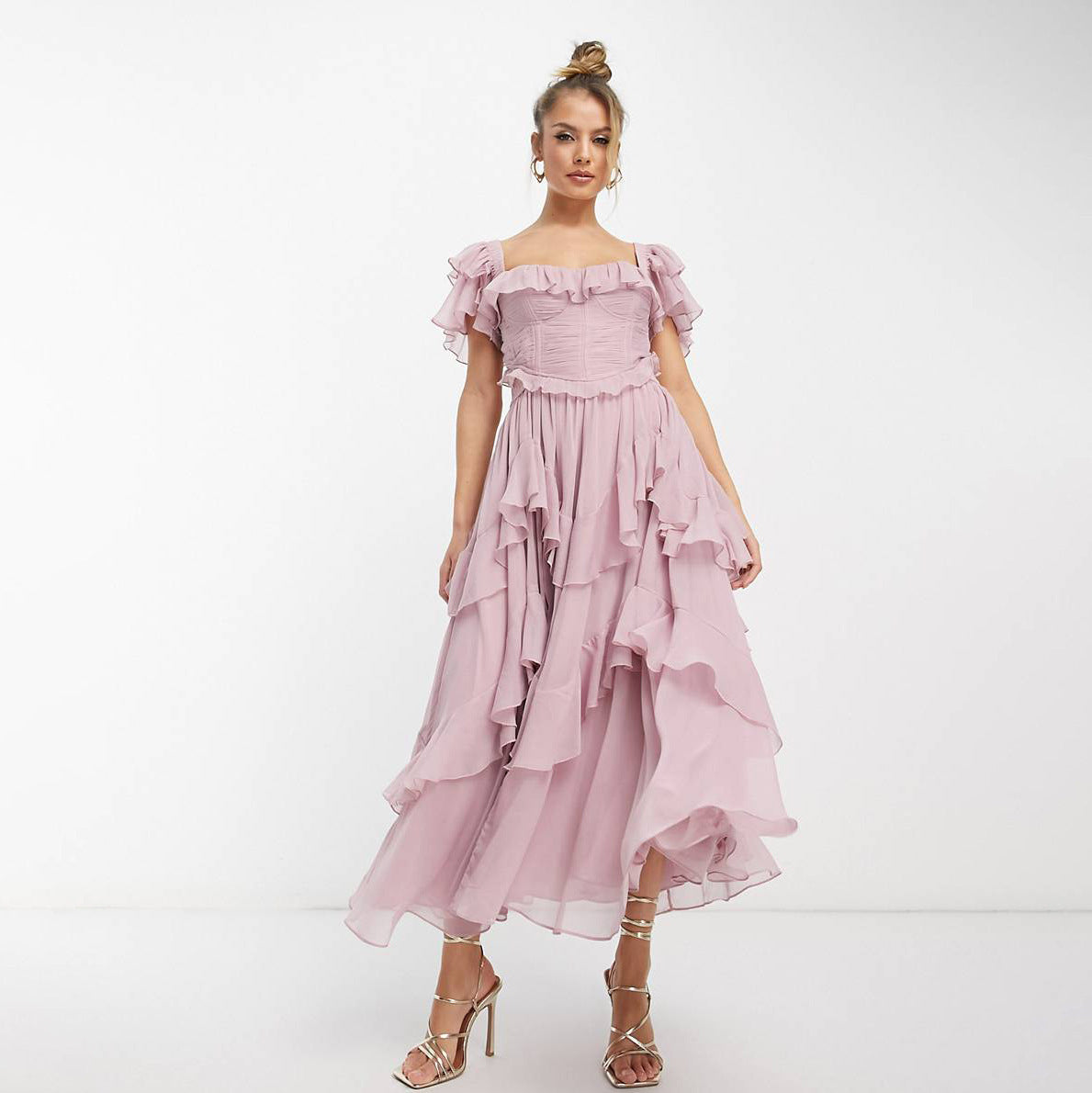 Woman wearing a pink off-shoulder dress with ruffles on a white background