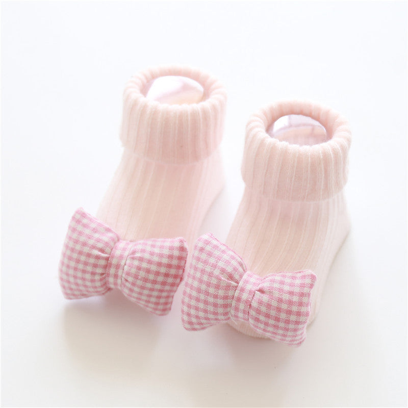 Pair of baby socks with pink gingham bows on a white background