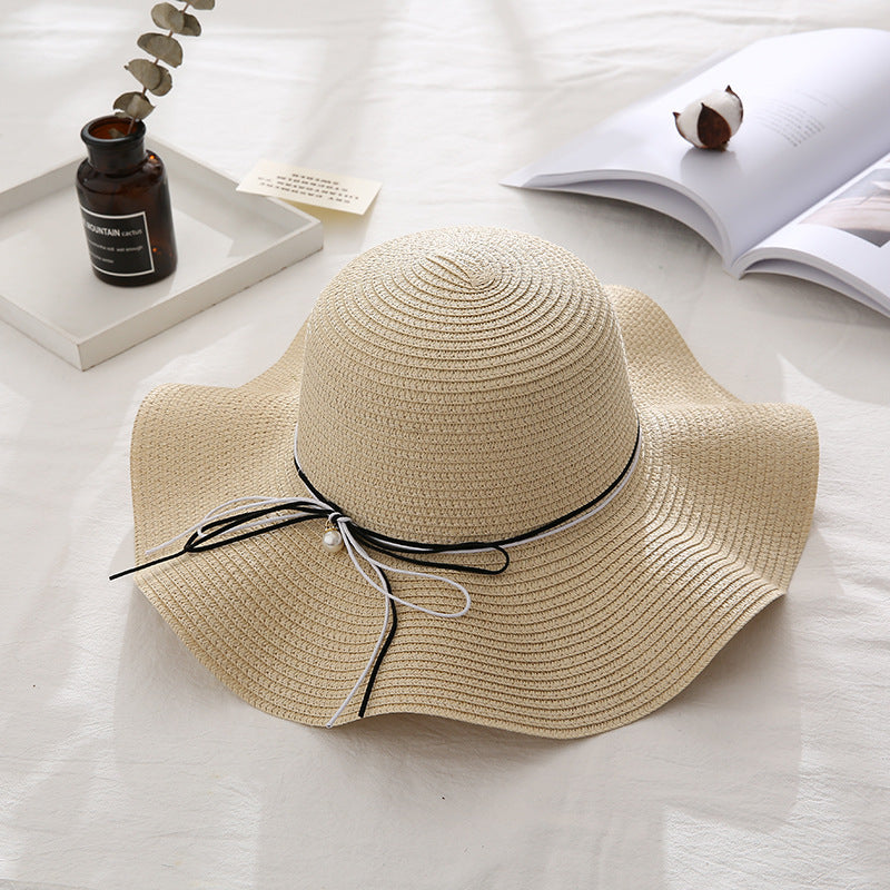 Beige straw hat with a black ribbon on a light surface