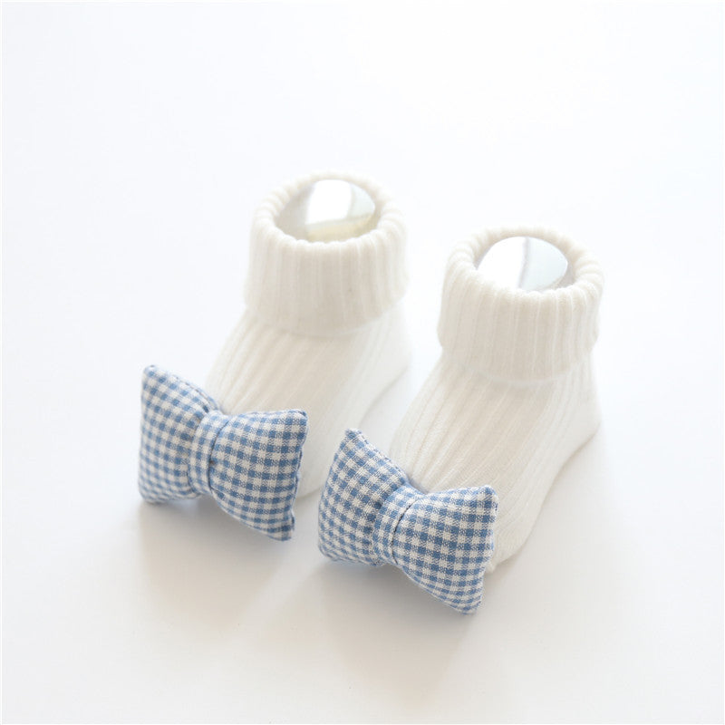 White baby booties with blue gingham bows on a white background