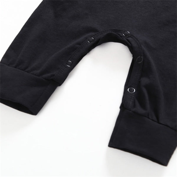 Close-up of a black baby onesie with buttons on a white background