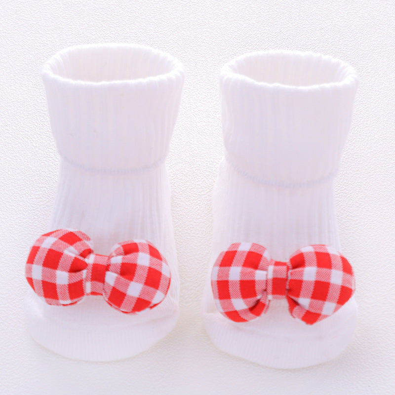 White baby shoes with red and white checkered bows on a light background