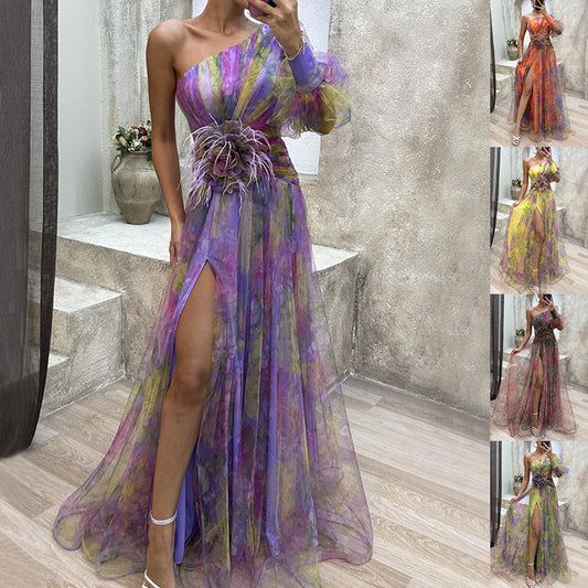 Multicolored one-shoulder dress with a slit on a wooden floor.