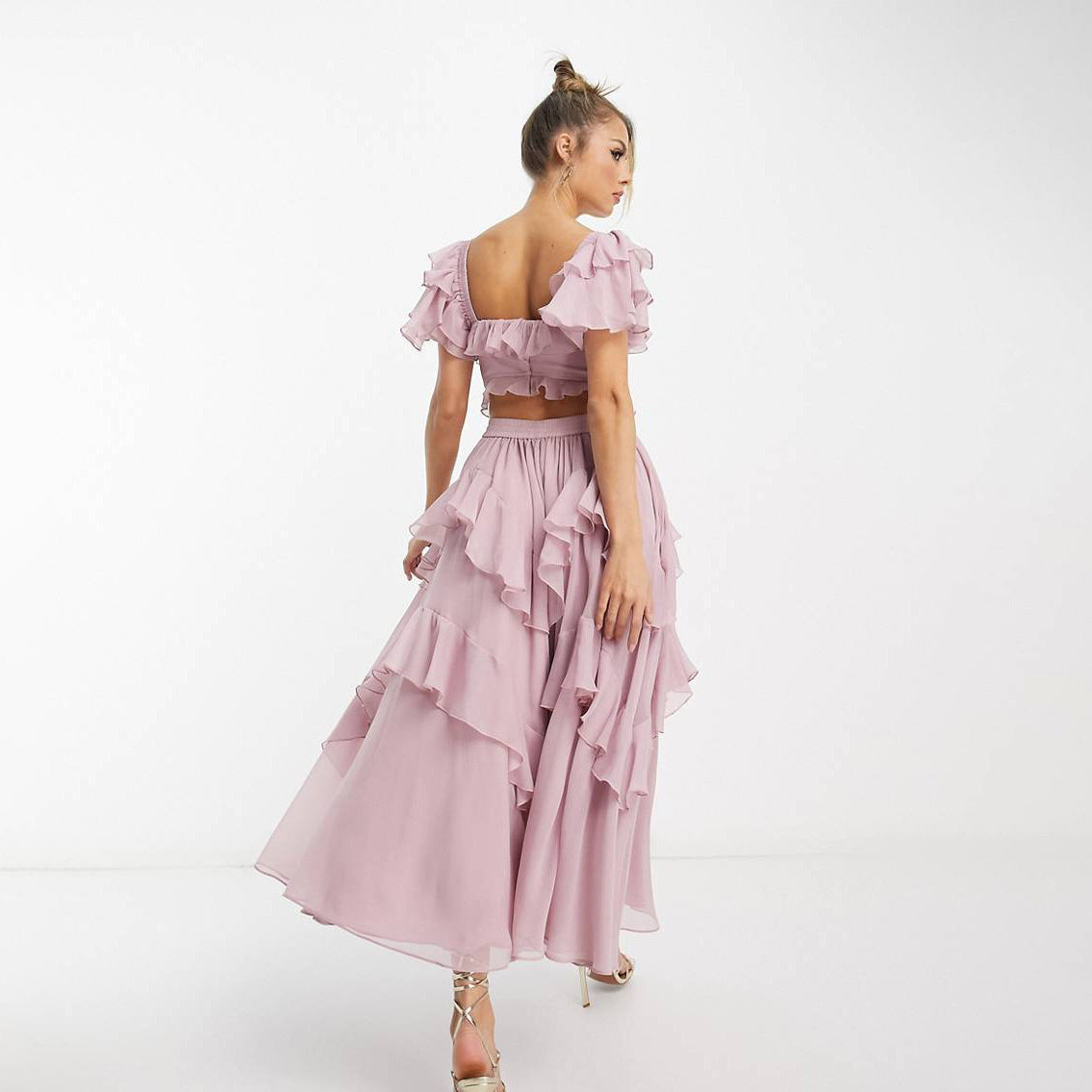 Woman wearing a pink ruffled dress on a white background