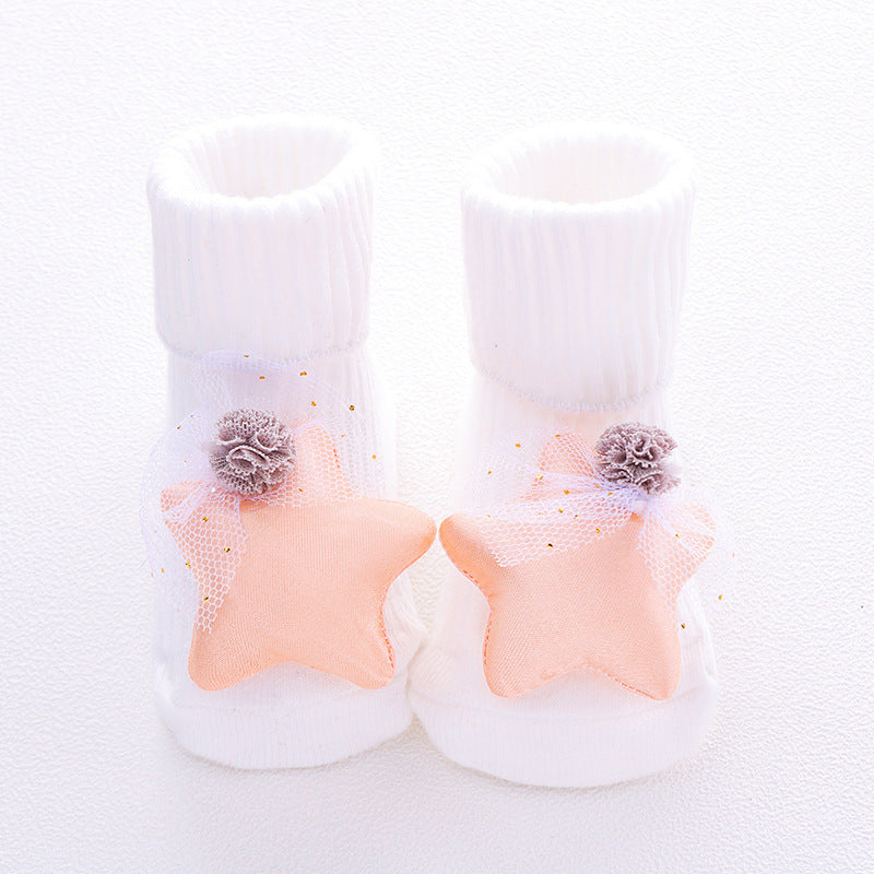 Pair of baby booties with star design and pom-poms on a white background
