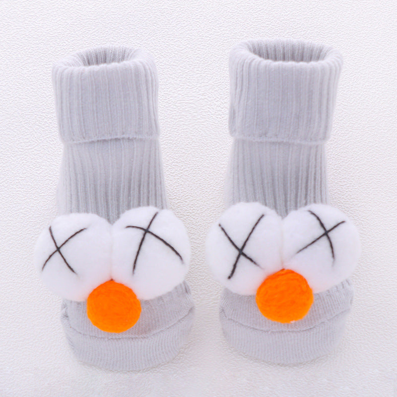 Gray baby socks with white bunny faces and orange noses on a light gray background