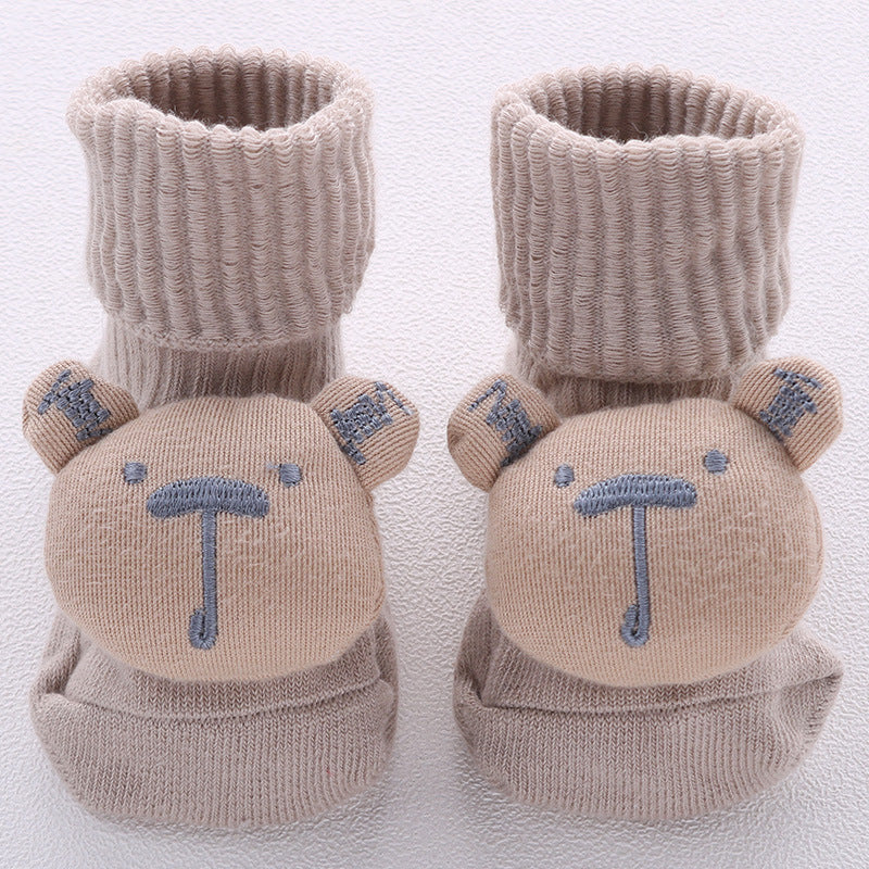 Pair of beige baby booties with bear faces and blue details on a white background
