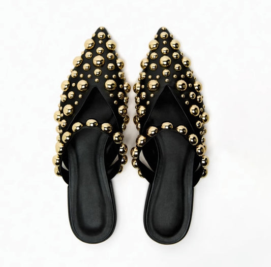 Black sandals with gold studs on a white background