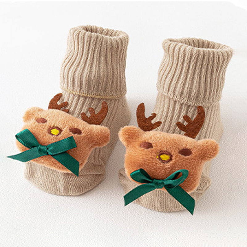 Pair of beige baby booties with teddy bear and antler design on a white background